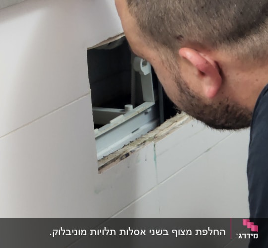 אדם בודק צנרת מאחורי קיר פתוח